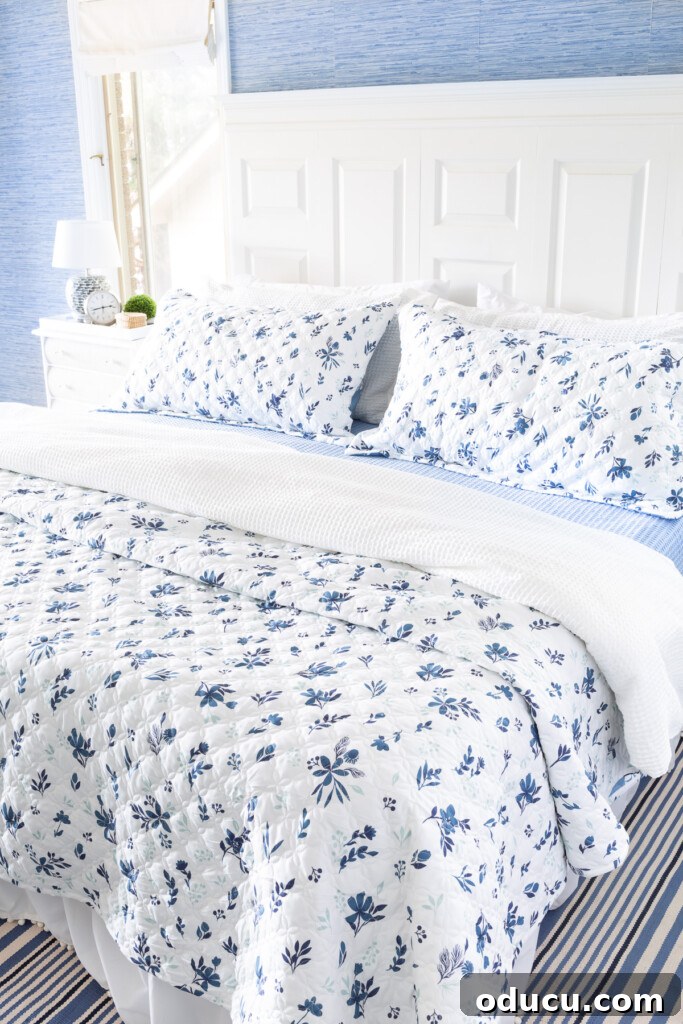 Bedroom Blooms: Your Instant Spring Refresh 3 A reversible floral bedspread and matching pillow shams in blue and white on a cozy bed.