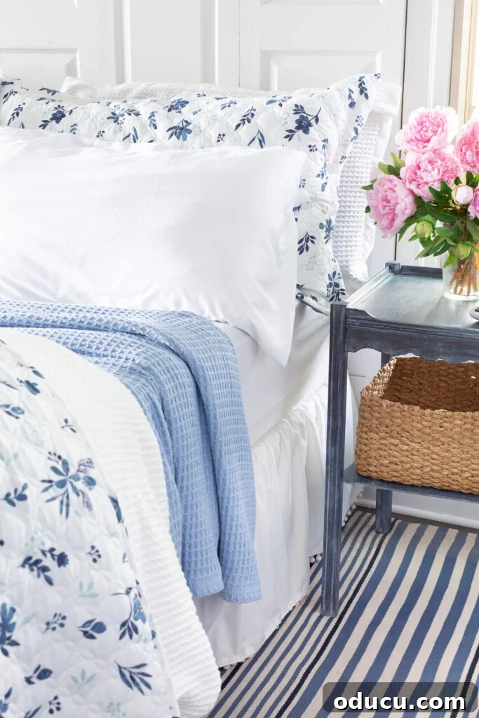 Bedroom Blooms: Your Instant Spring Refresh 9 A king size bed made up with a reversible floral bedspread, waffle weave duvet cover, and a sky blue blanket, creating a luxurious layered look.