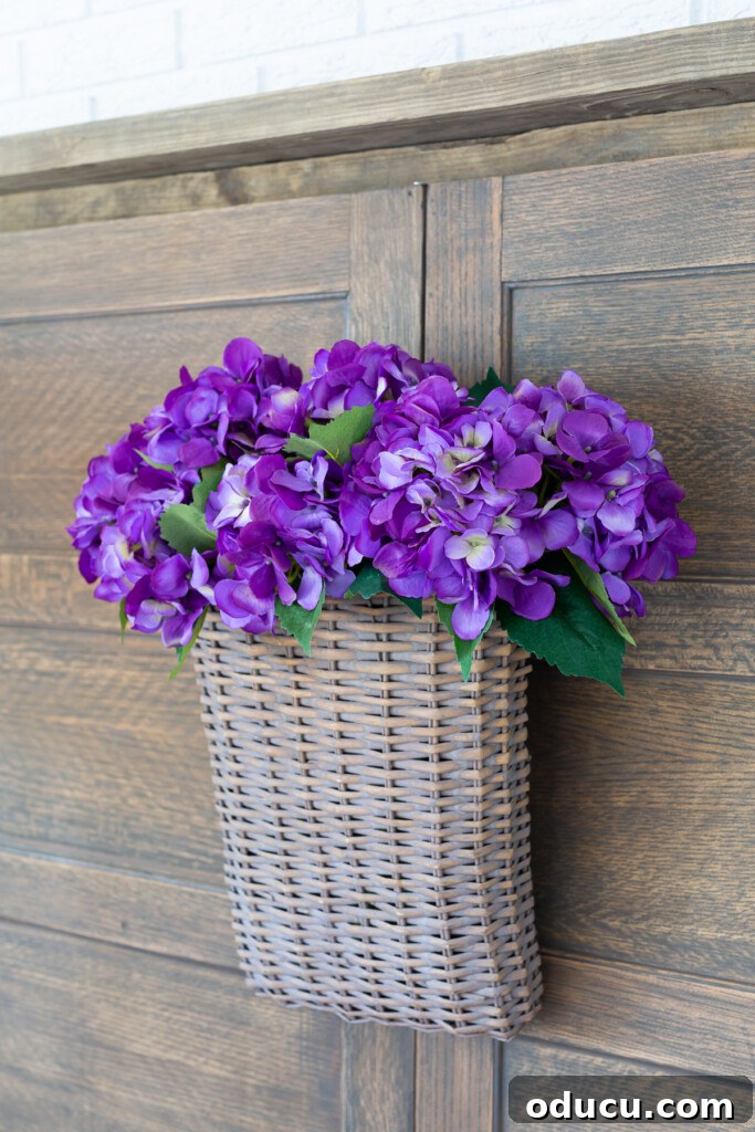 Found Treasure: My Living Room's Fireplace Cover 4 A decorative wall basket filled with vibrant purple hydrangeas, thoughtfully hung on reclaimed wood panels repurposed as a stylish fireplace cover, adding a pop of color.