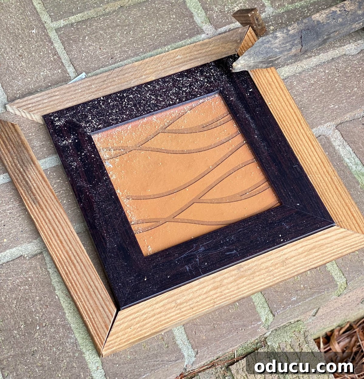 Scrap wood cut and mitered to fit around a plain black photo frame, indicating the enlargement process.