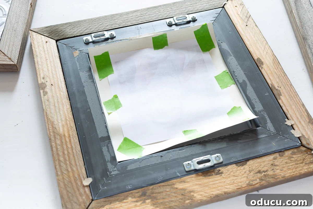 Demonstration of how to close up the back of a picture frame, specifically attaching a photo to a mat with masking tape.