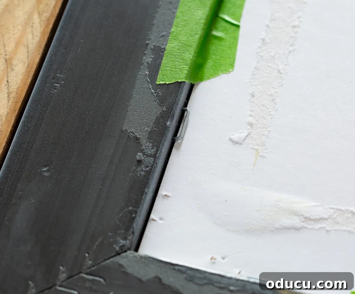 Demonstration of how to secure a photo in a photo frame using a staple gun and masking tape for a robust backing.