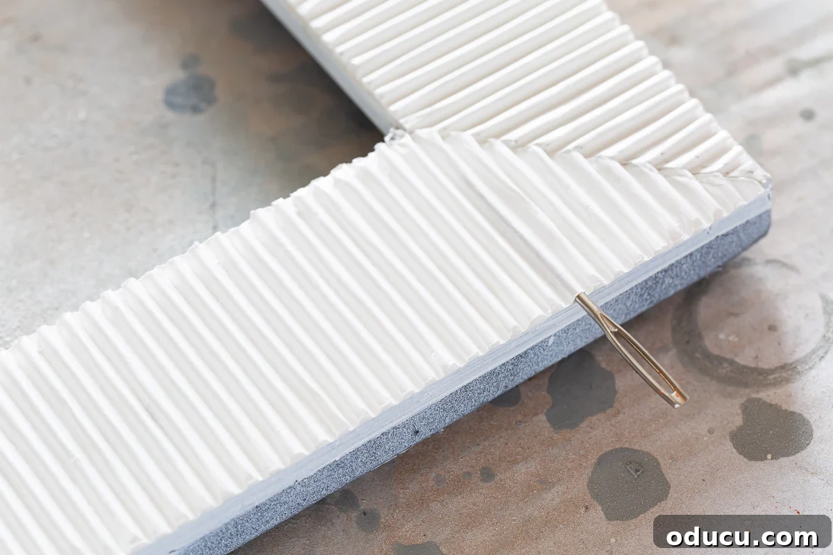 A helpful tip on how to open and fix flattened corrugated cardboard using a sewing needle, restoring its texture for crafts.