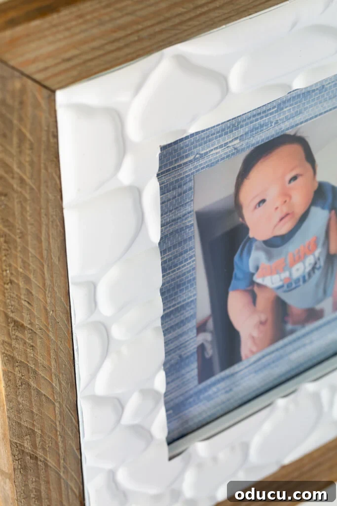 Thrift store picture frame makeover, featuring textured faux stone adhesive tiles from the Dollar Store used to decorate a repurposed frame.