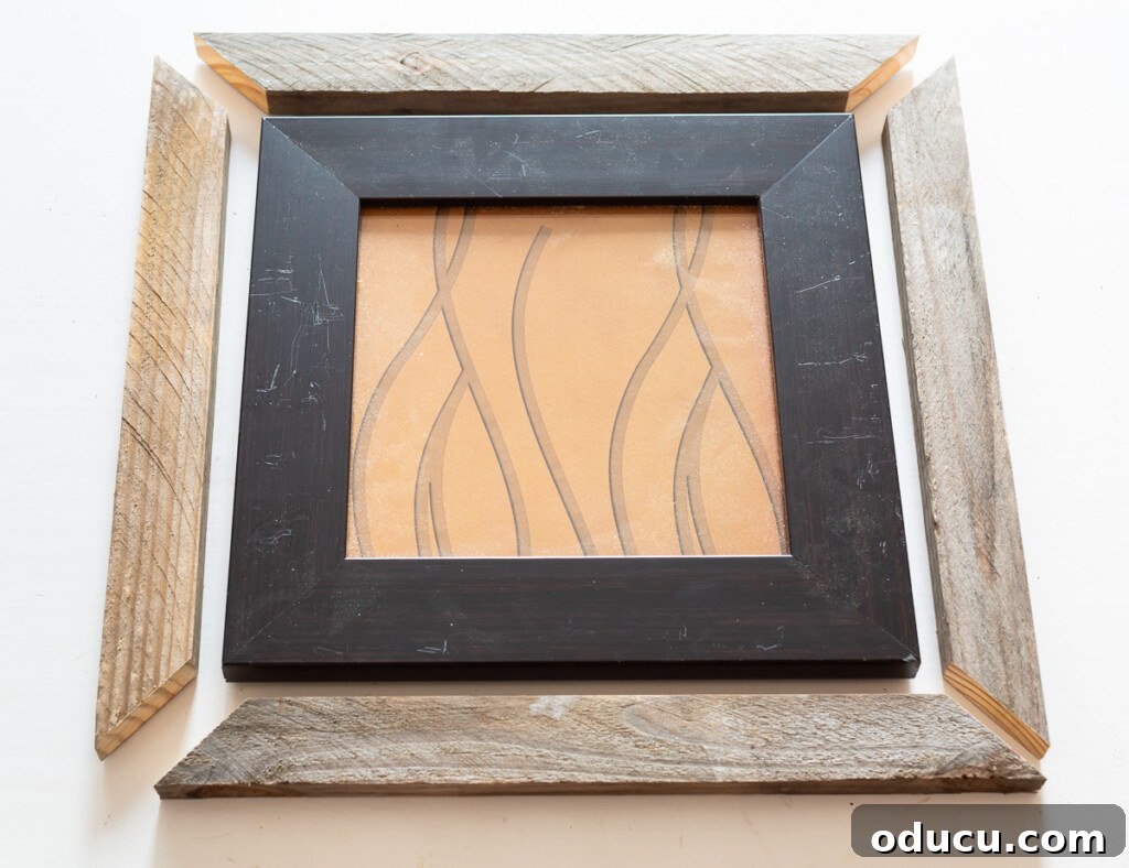 Scrap wood cut to place around an intact thrift store frame to make the frame appear larger and more substantial.