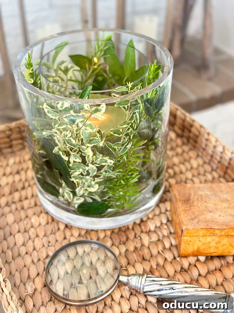 Effortless Greenery Candle Vases 3 A charming glass candle vase DIY, crafted from two nested vases and filled with fresh herbs and greenery, serving as a delightful summer table decoration.