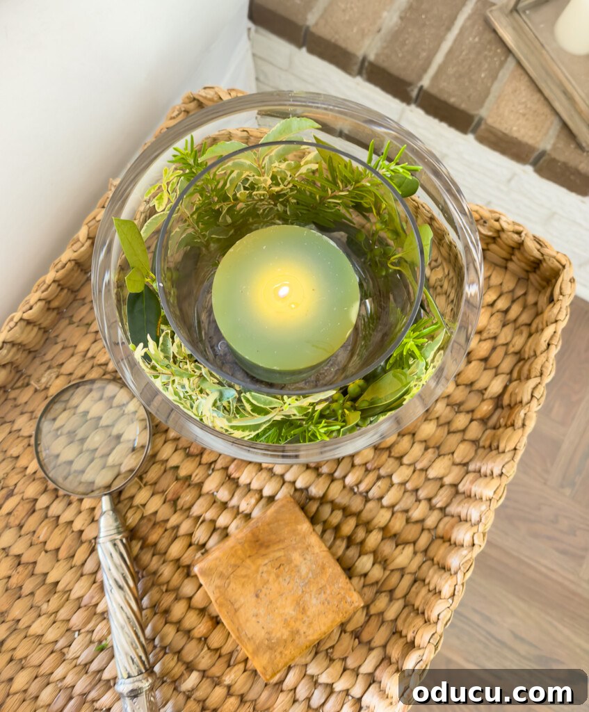 Effortless Greenery Candle Vases 9 A top-down view of a DIY glass candle vase, beautifully arranged on a wicker tray table, highlighting its natural elegance.