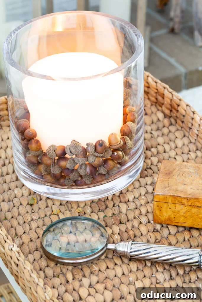 Creating a Cozy Fall Living Room Sanctuary 14 faux acorns in glass candle vase on table decorated for fall.