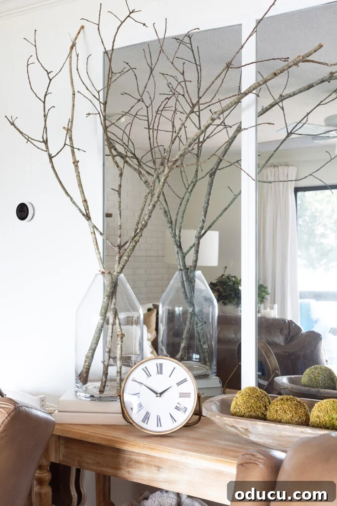 Tree branches in a large glass vase on a console table.