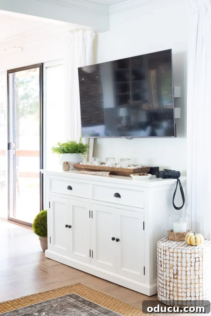Black flat screen TV mounted on wall with white sideboard underneath.