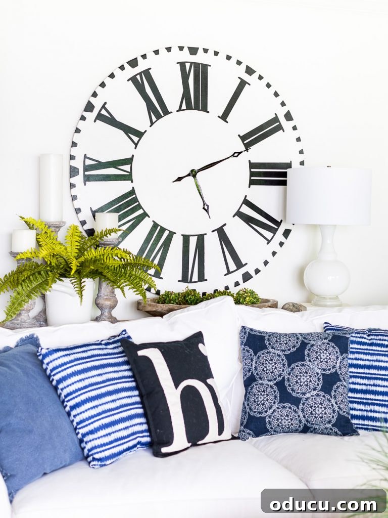 White faced Roman numeral oversized clock on wall in blue and white decorated living room