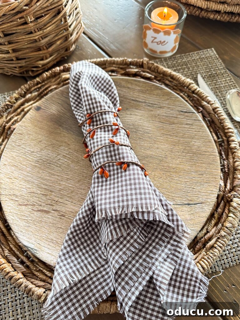 Simple & Stunning Thanksgiving Table Settings 13 Looking down at a Thanksgiving place setting in a rustic style with a berry garland napkin ring