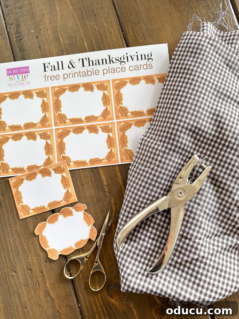Simple & Stunning Thanksgiving Table Settings 19 Fall & Thanksgiving free printable place cards, brown and white gingham fabric, scissors, and hole punch gathered on a table