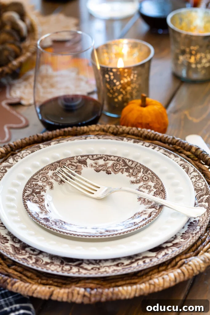 Simple & Stunning Thanksgiving Table Settings 8 Brown and white plates on a dining table with woven chargers