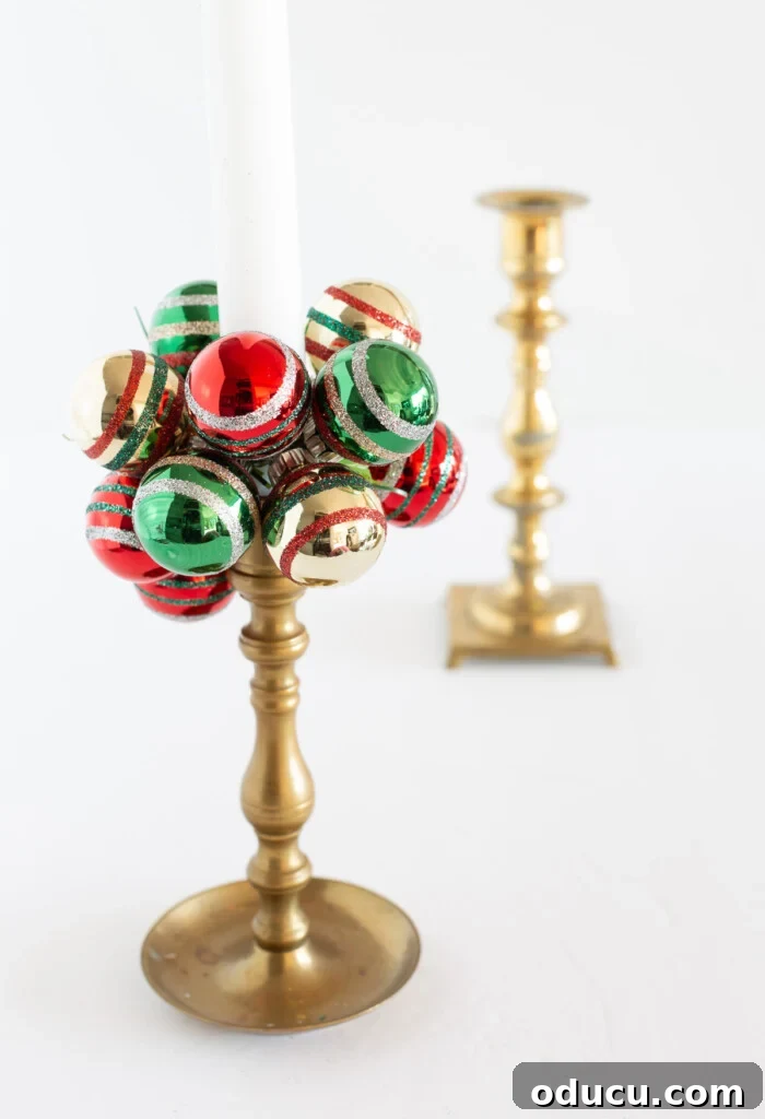 Simple Steps to Gorgeous Christmas Taper Candle Rings 9 A classic brass candle holder beautifully decorated with a DIY taper candle collar, featuring vibrant green, red, and gold mini Shiny Brite ball ornaments.