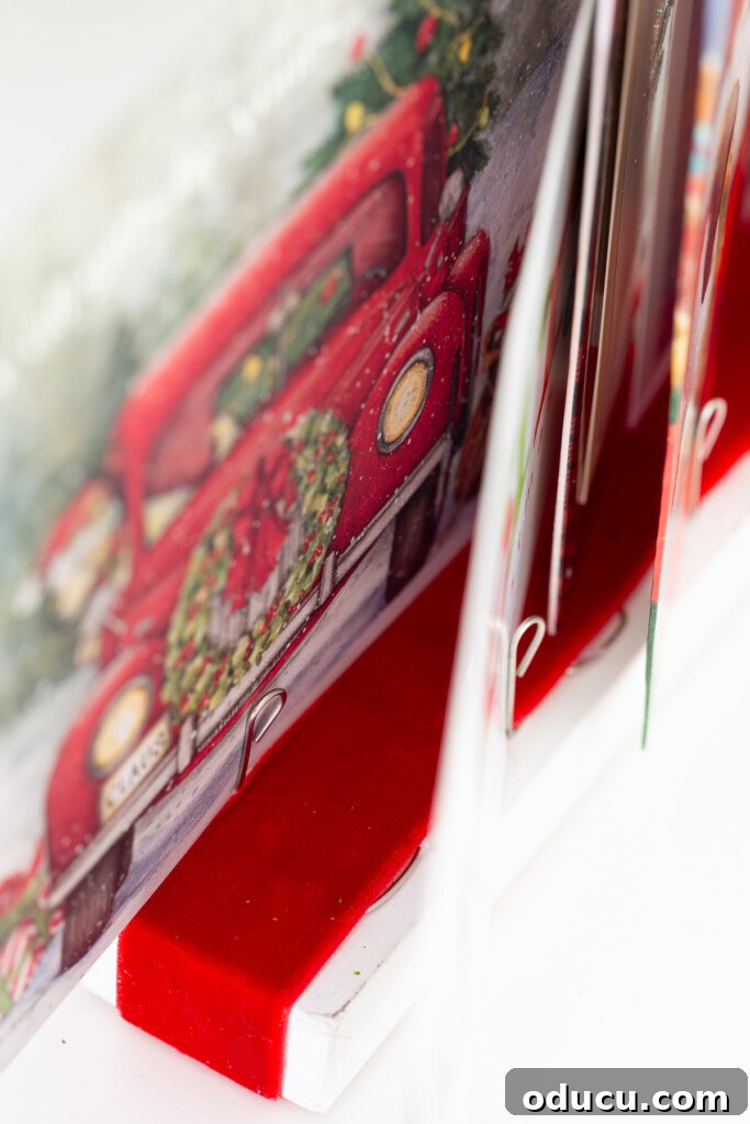 Showcase Your Holiday Cards: DIY Mantel & Table Display 13 Close-up showing how to attach Christmas cards to the DIY card holder, emphasizing stability for larger cards.
