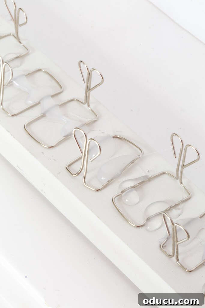 Showcase Your Holiday Cards: DIY Mantel & Table Display 9 Close-up of owl style paper clips being attached to scrap wood for a holiday card holder.