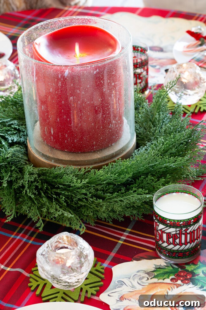 Joyful and Merry Christmas Dinner Table 6 Large 6x6 inch battery-operated red candle surrounded by a faux cedar wreath, serving as a Christmas table centerpiece on a round dining table.