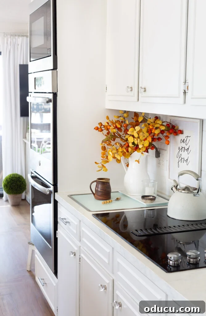 A small white kitchen wall decorated for fall, showing the versatility of a vase that can hold winter white floral arrangements or seasonal decor.