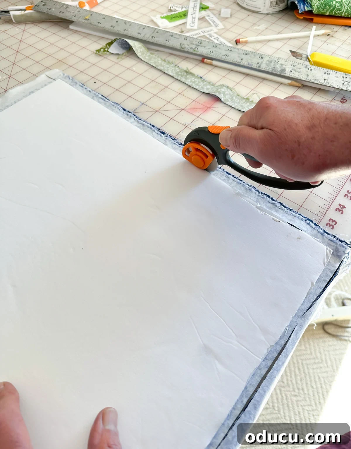 Cutting out two pieces of fabric using a foam board template and a rotary cutter, demonstrating an efficient cutting technique for cloth napkins.