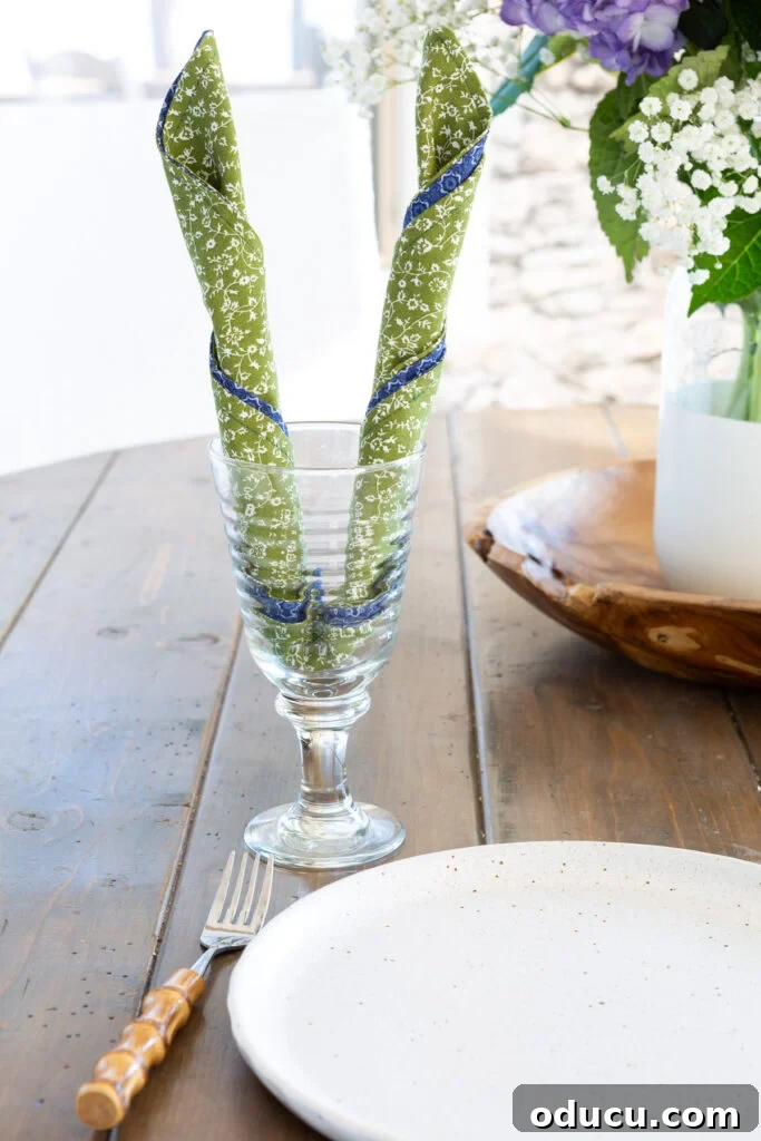 Whip Up Wonderful Napkins: A Simple Guide to Colorful Table Decor 7 A creative way to fold a napkin for impact on a dining table, rolled into 'bunny ears' and placed in a stemmed drinking glass.