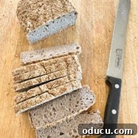 Looking down at a golden-brown loaf and several perfectly sliced pieces of homemade buckwheat bread.