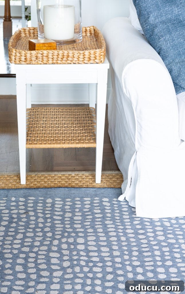 Elevating My Living Room with Area Rugs 10 A blue and white modern coastal decorated living room, highlighting the layered rugs and decorative pillows.