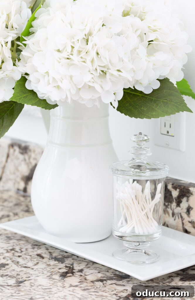 Primary Bathroom Sanctuary Unveiled 20 white hydrangeas in a white pitcher on a bathroom counter.