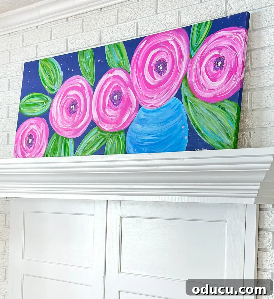 Paint Your Own Canvas: Simple Art for Everyone 4 DIY wall art painting of big pink flowers on a dark blue background placed on a living room mantel.