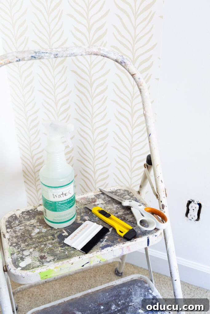 Walls of Welcome 13 An organized collection of all the necessary supplies for installing Love vs Design wallpaper, including tools for prep, application, and finishing, highlighted by a helpful tip for protecting electrical outlets.