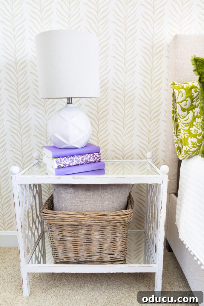 Walls of Welcome 15 A pristine white night table positioned in a beautifully decorated bedroom, featuring an accent wall covered with Love vs Design's elegant Vine Thread wallpaper pattern.