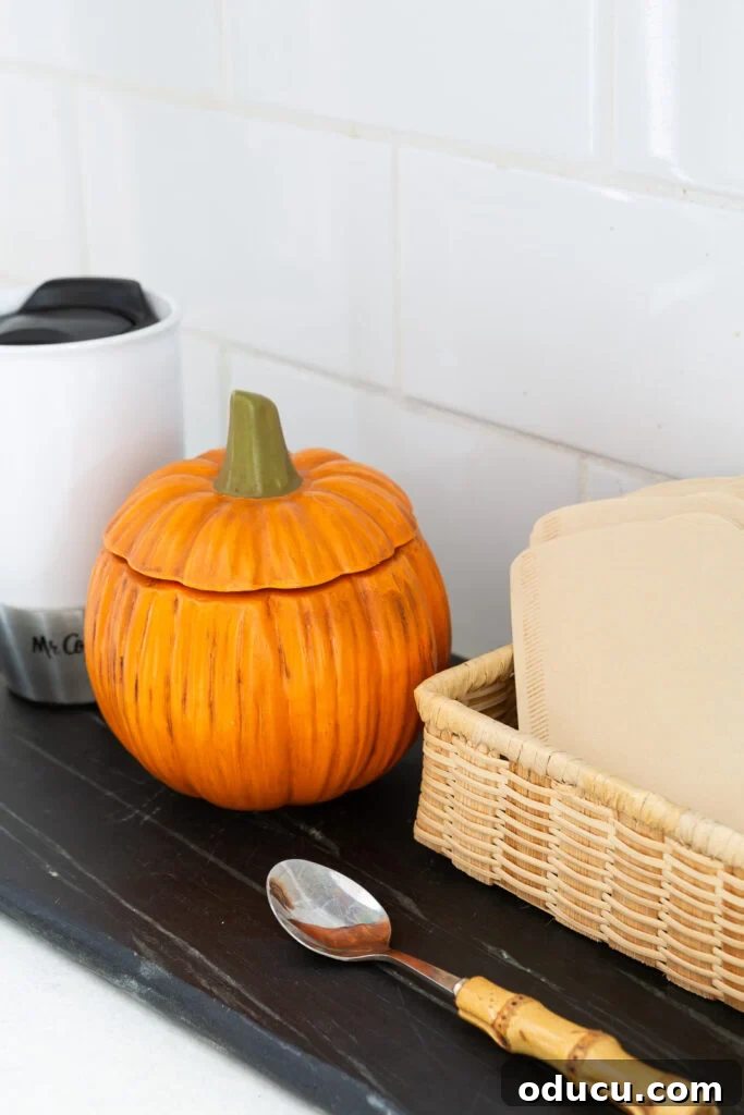 Hold Off on Fall Decorating Try This Alternative 11 orange ceramic pumpkin bowl with lid to hold sugar for the fall season placed on a kitchen counter coffee station.