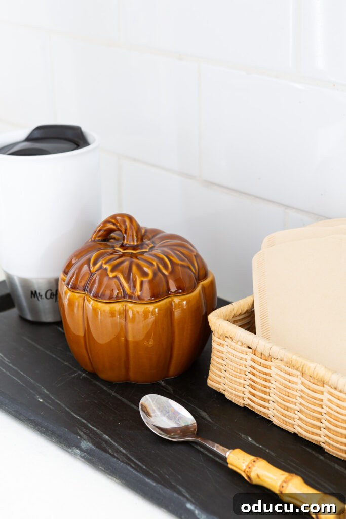 Hold Off on Fall Decorating Try This Alternative 12 brown ceramic pumpkin bowl with lid to hold sugar for the fall season placed on a kitchen counter coffee station.