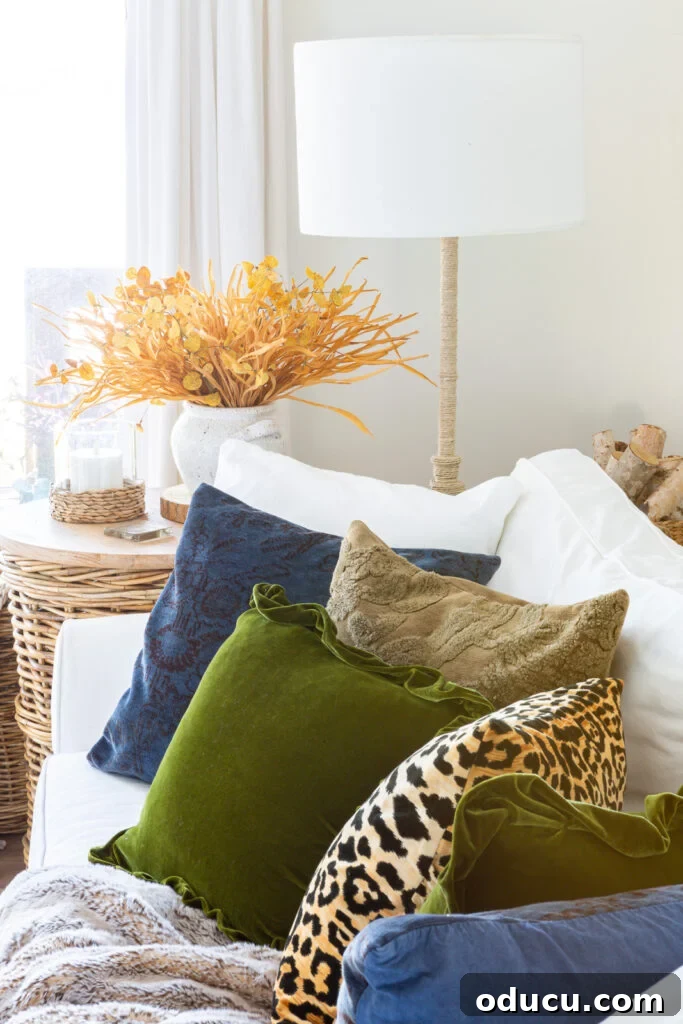 Cozy Autumn Vibes: Living Room Refresh 2 Line up of pretty fall throw pillows on a white sofa with a wicker table and floor lamp at the end.