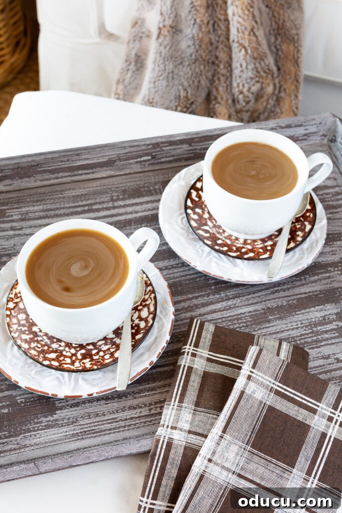 Cozy Autumn Vibes: Living Room Refresh 13 two white mugs on a brown wood tray on an ottoman. Mugs are on brown splatterware plates with coffee in them.