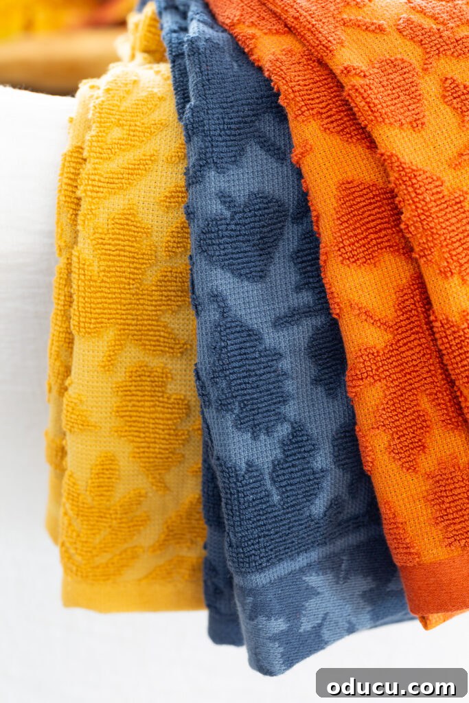 Cozy Autumn Vibes: Living Room Refresh 3 3 fall hued dishtowels with a textured leaves draped over a chair.