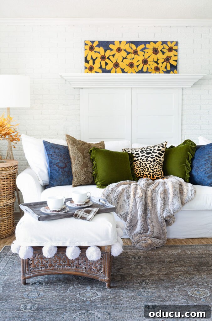 Cozy Autumn Vibes: Living Room Refresh 4 simple fall decor using throw pillows on a sofa in a white room with blue, green and burnt yellow accents.
