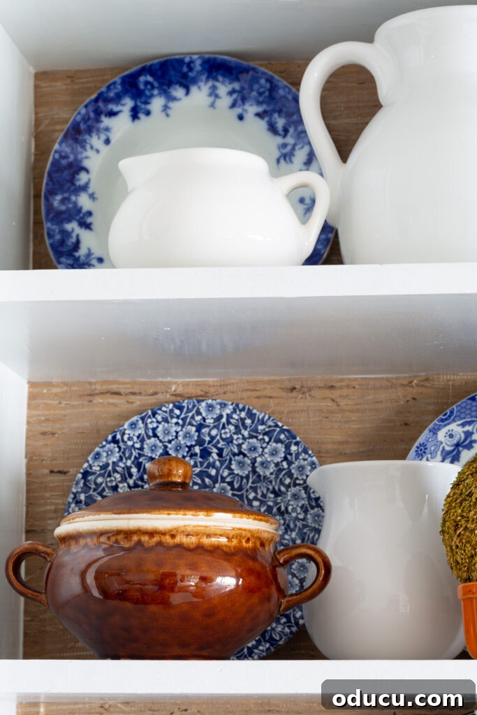Fall Kitchen Shelves Get a Wallpaper Makeover 14 Fall colored kitchen items displayed on open shelves in a small kitchen decorated for fall.
