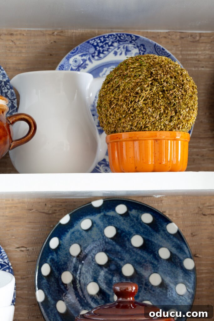 Fall Kitchen Shelves Get a Wallpaper Makeover 15 Fall colored kitchen items displayed on open shelves in a small kitchen decorated for fall.