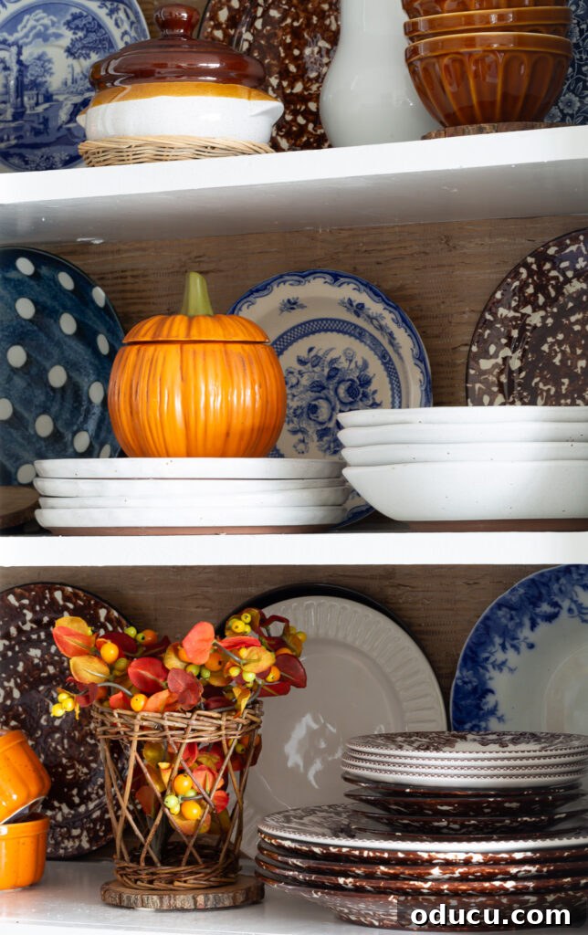 Fall Kitchen Shelves Get a Wallpaper Makeover 16 Fall colored kitchen items displayed on open shelves in a small kitchen decorated for fall.