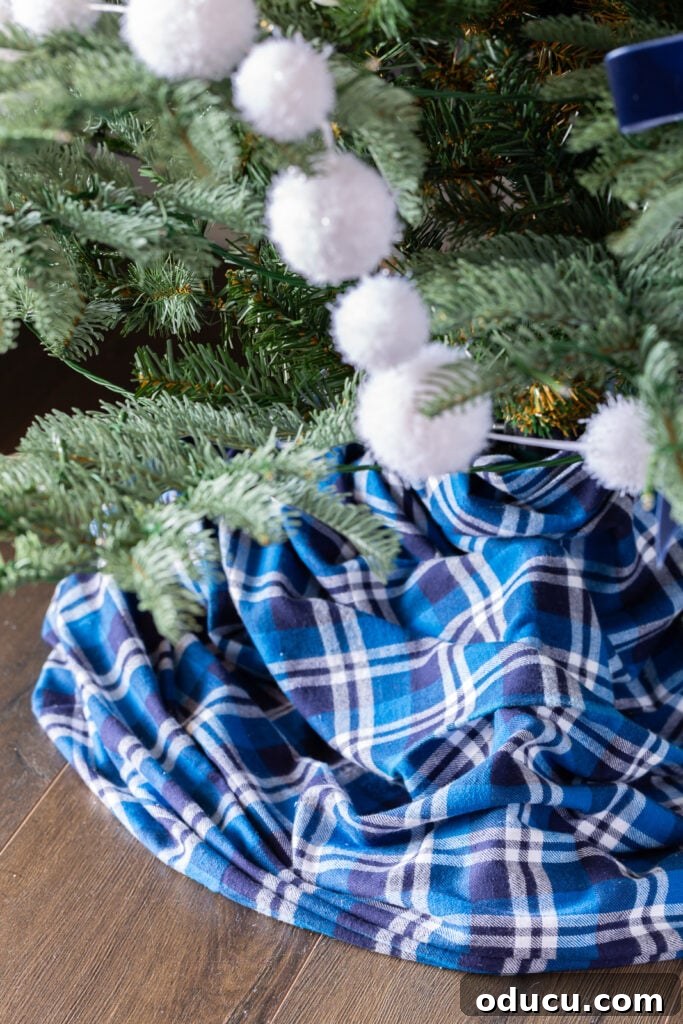 The King of My Christmas 13 Christmas tree skirt made by wrapping blue and white plaid fabric yardage around tree stand.