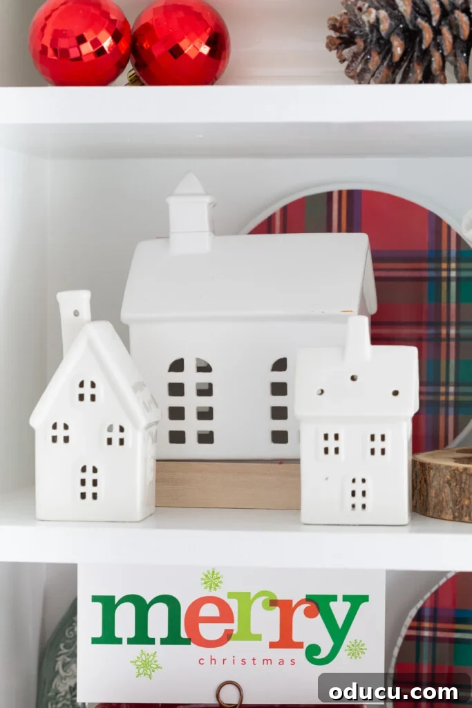 Tealight Village Magic: Fall and Holiday Decor 2 Three elegant white ceramic light-up houses artfully displayed on open kitchen shelving, bringing a festive glow to the heart of the home.