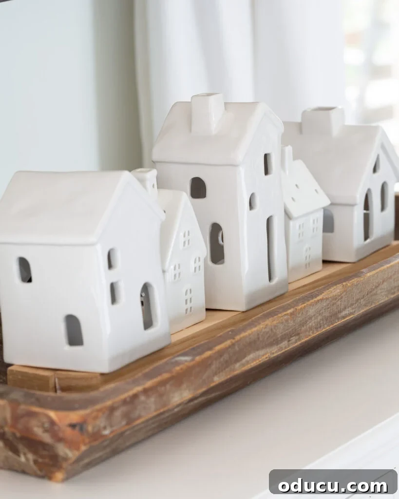 Tealight Village Magic: Fall and Holiday Decor 3 A charming display of white ceramic tea light houses artfully arranged in a long dough bowl on a living room console table, creating a cozy ambiance.