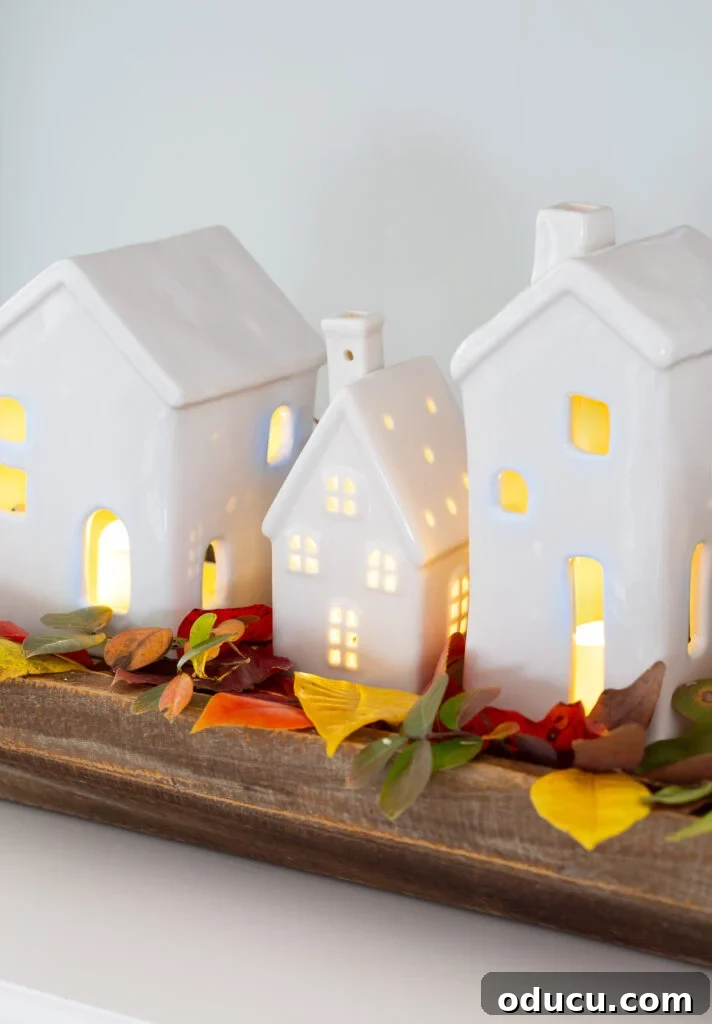 Tealight Village Magic: Fall and Holiday Decor 9 A charming light-up white ceramic village creates a festive fall decoration on a table, blending autumn warmth with holiday anticipation.