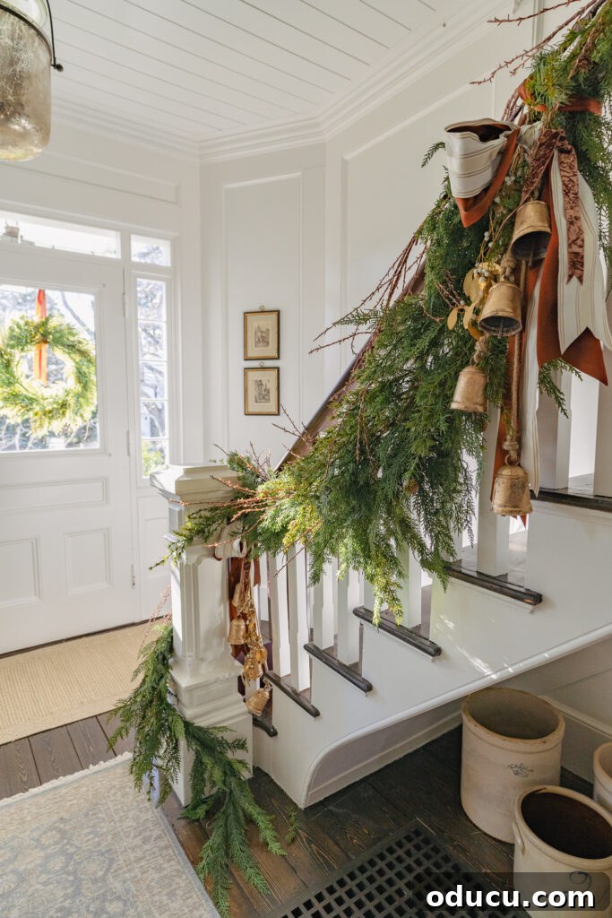 Chic Finds 220 2 Elegantly decorated staircase for Christmas with green garland and brass bells, evoking a festive, traditional holiday spirit.