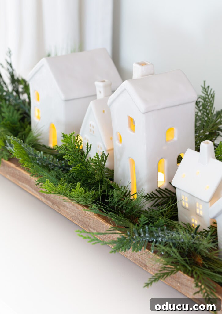 Decking the Halls for the Holidays 5 Christmas tabletop display using white ceramic houses lined up in a dough bowl with greenery around them.