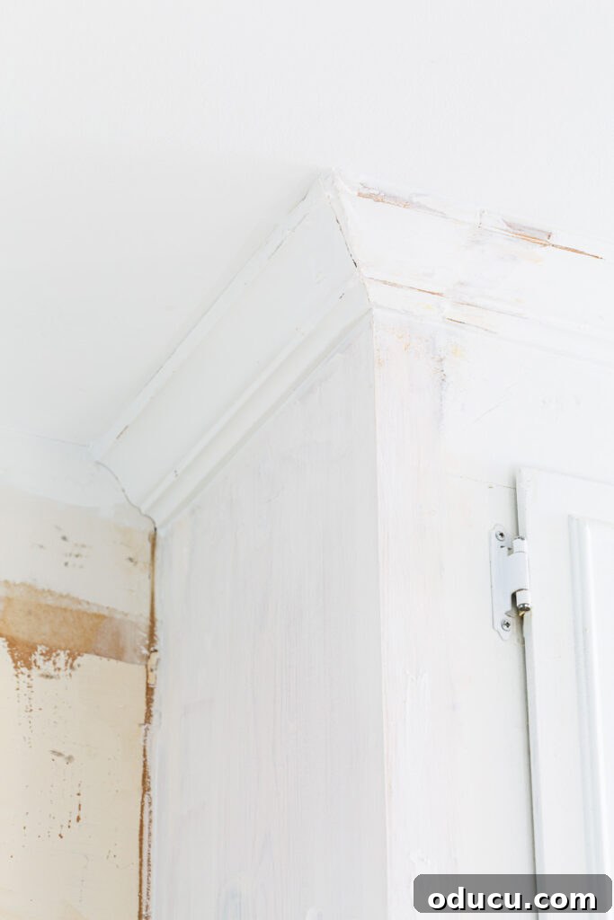 My Kitchen's Stunning Spacious Makeover 16 Process of adding molding back to an upper kitchen cabinet after ceiling renovation.