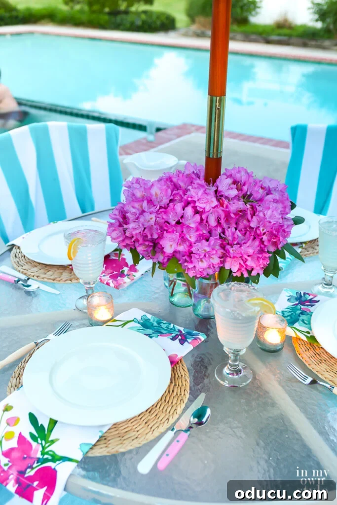 faux flower centerpiece on a round outdoor table with an umbrella pole in the center of the table.