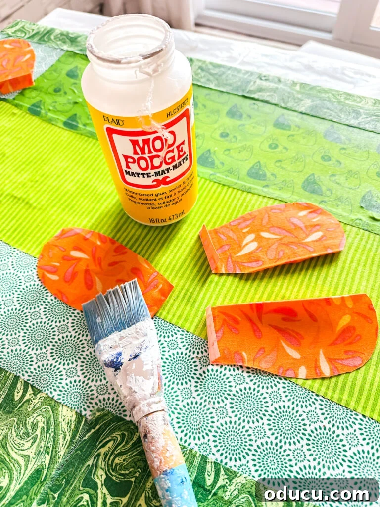 Brushing Mod Podge on fabric flower petals to attach to canvas.